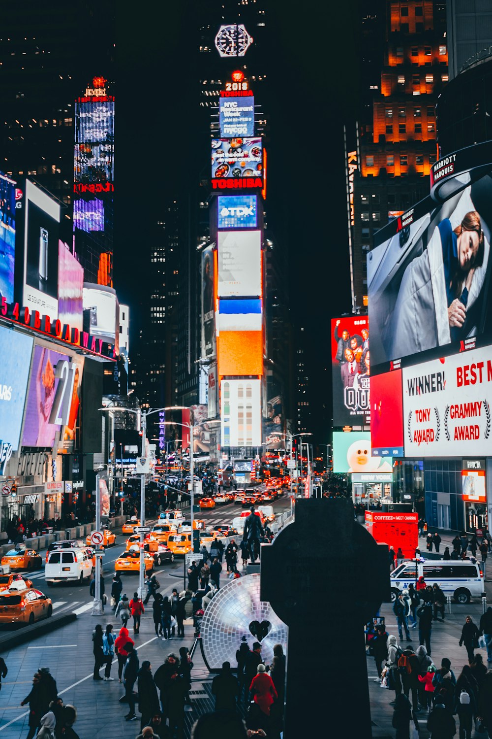 persone che camminano per strada circondata da alti edifici durante la notte