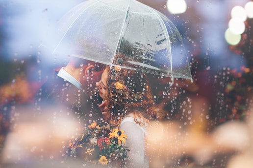 Une mariée et un marié s’embrassent sous la pluie sous un parapluie