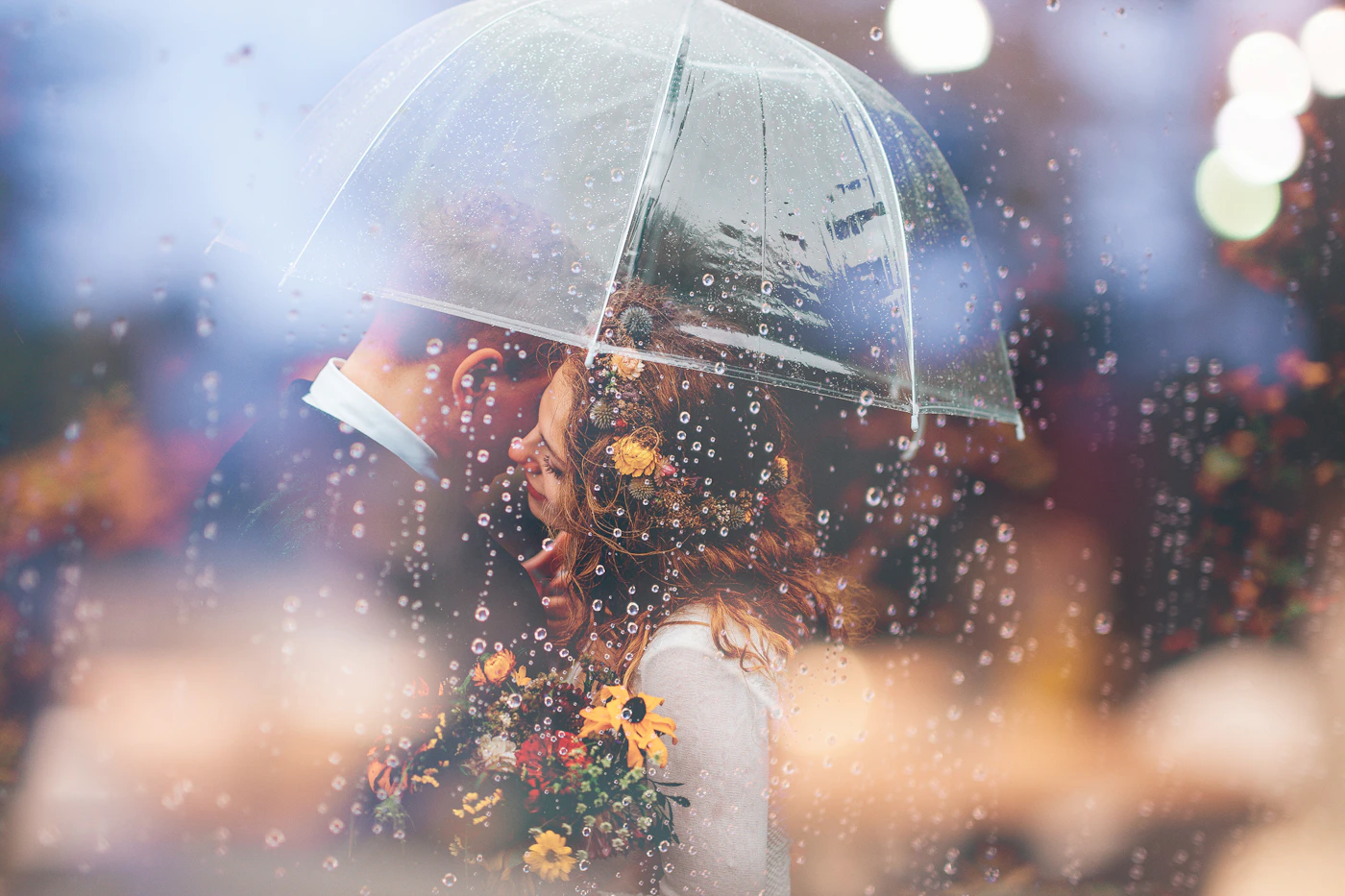 Bride and groom sharing a kiss in the rain with misty mountains in the background