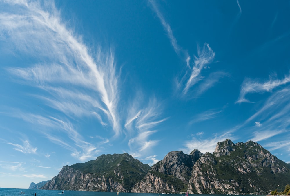 green tree-covered rocky mountain island under blue skies