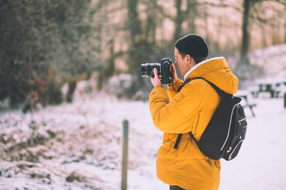 man wearing brown pull-over jacket using black camera