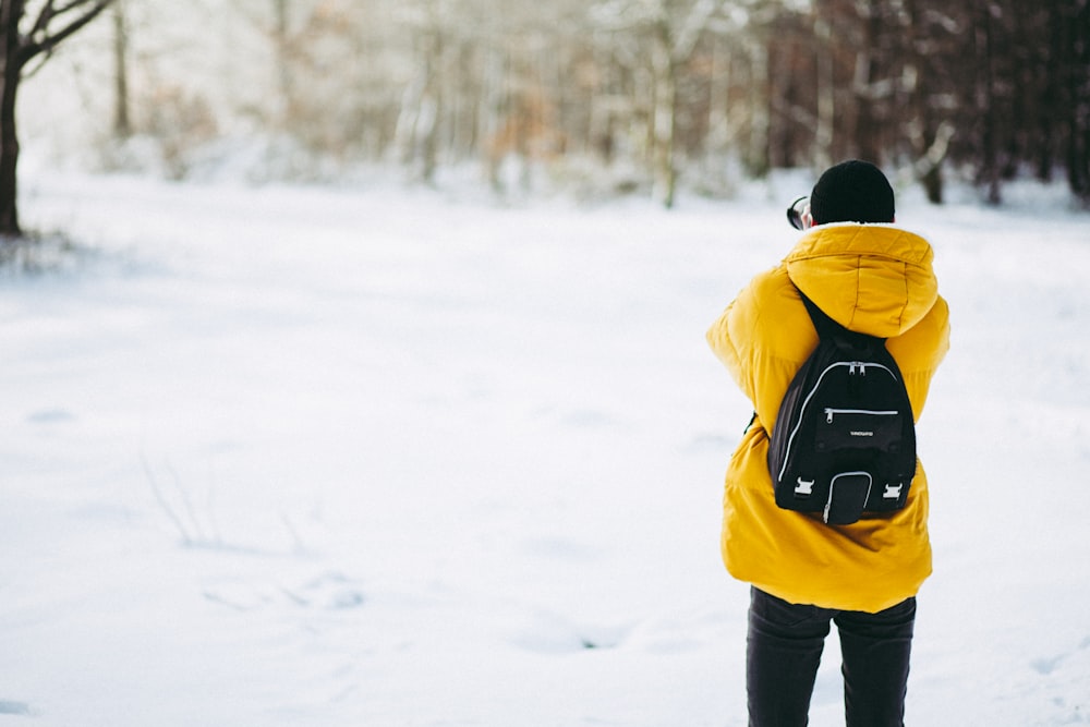 pessoa vestindo casaco em pé no campo de neve durante o dia