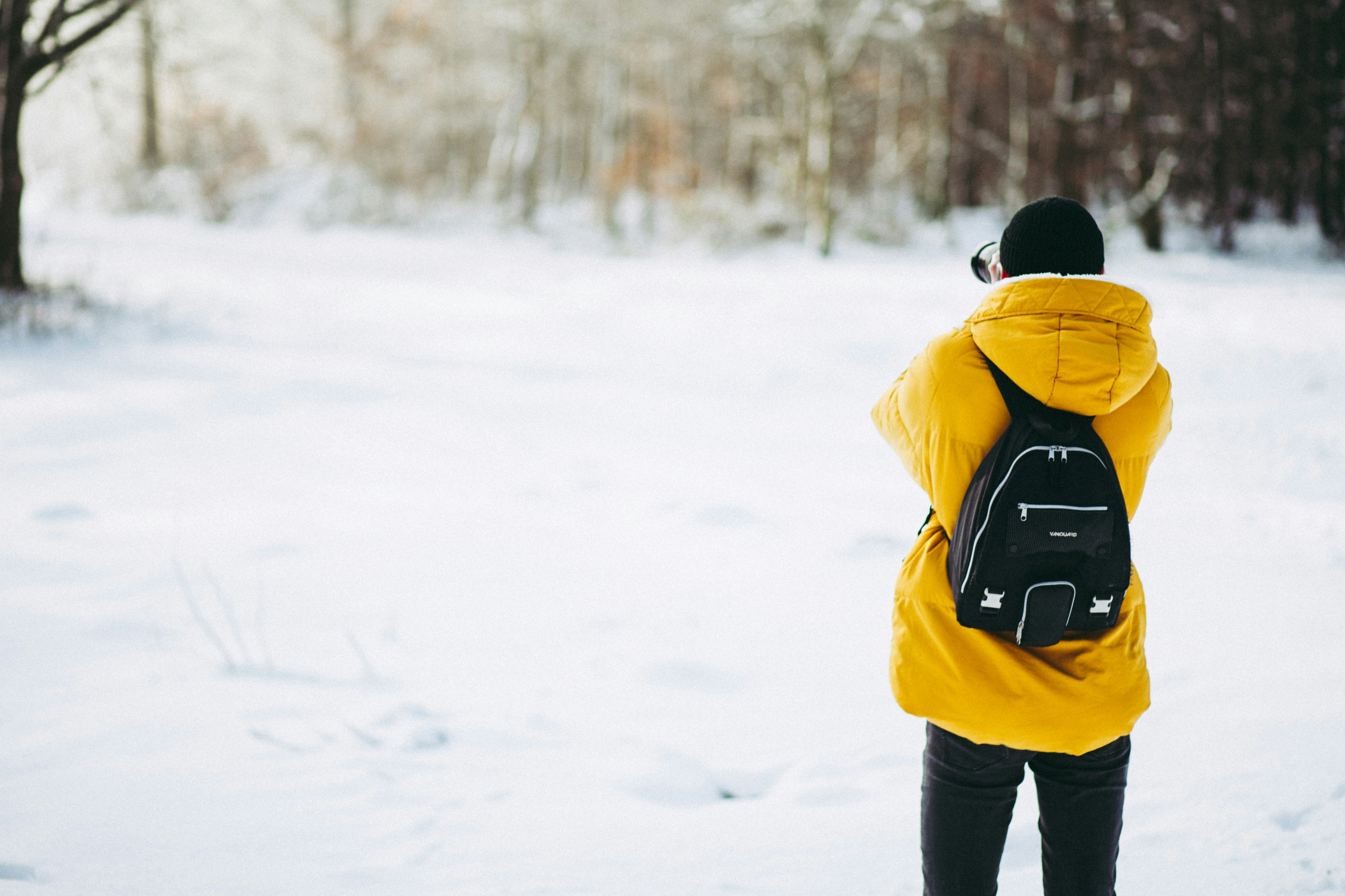 person wearing coat standing on field of snow during daytime