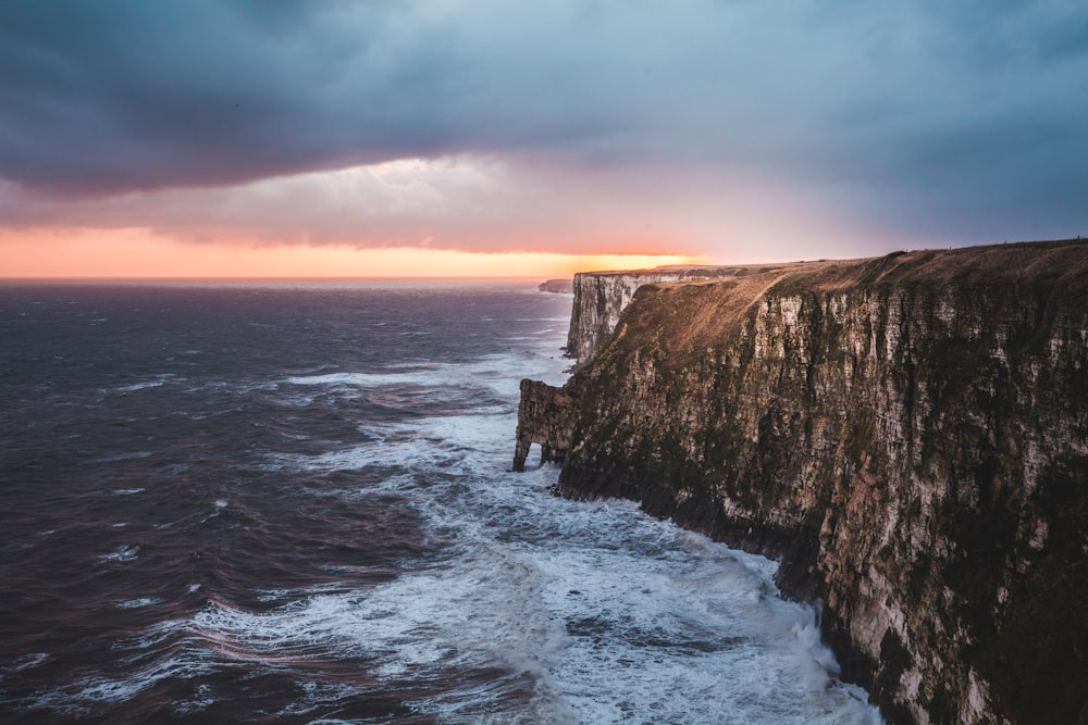 gray rocky mountain beside sea at golden hour