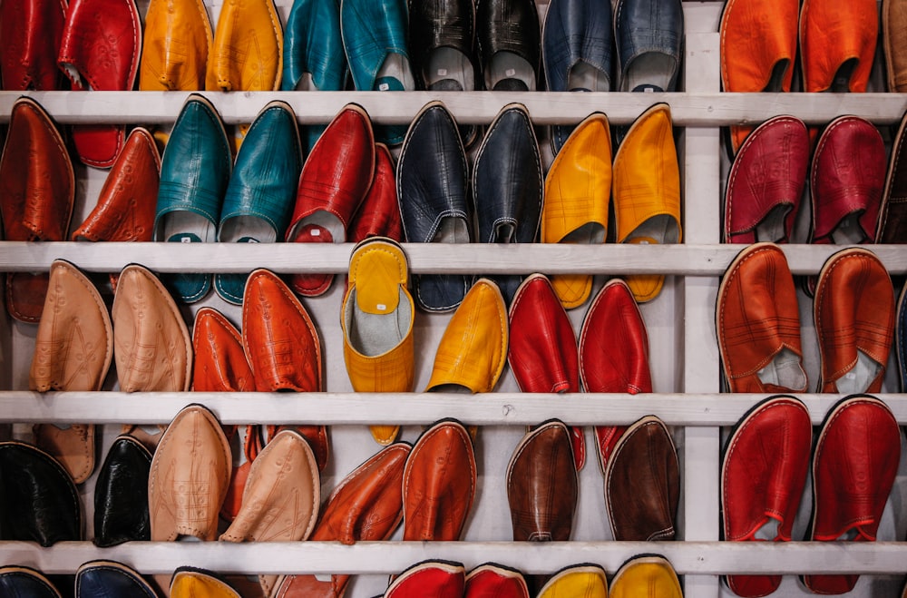 Lote de zapatos de colores variados en estante de madera blanca