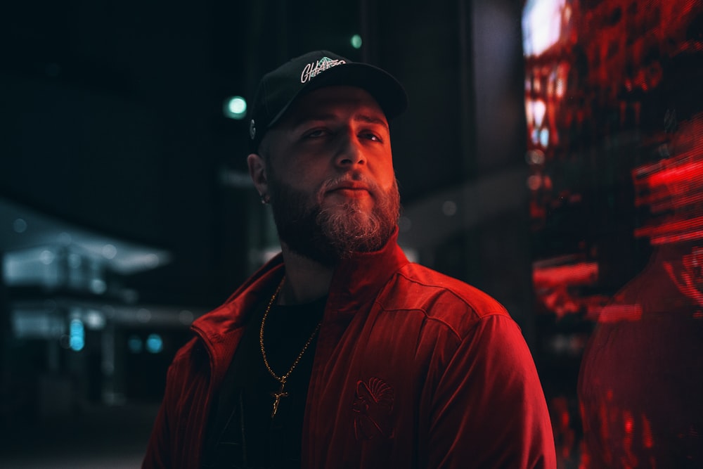 man wearing red collared top and black cap