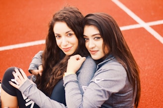 two women hugging each other on orange pavement