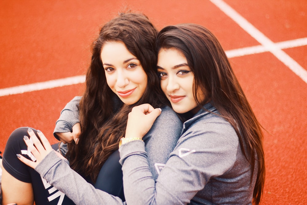 two women hugging each other on orange pavement