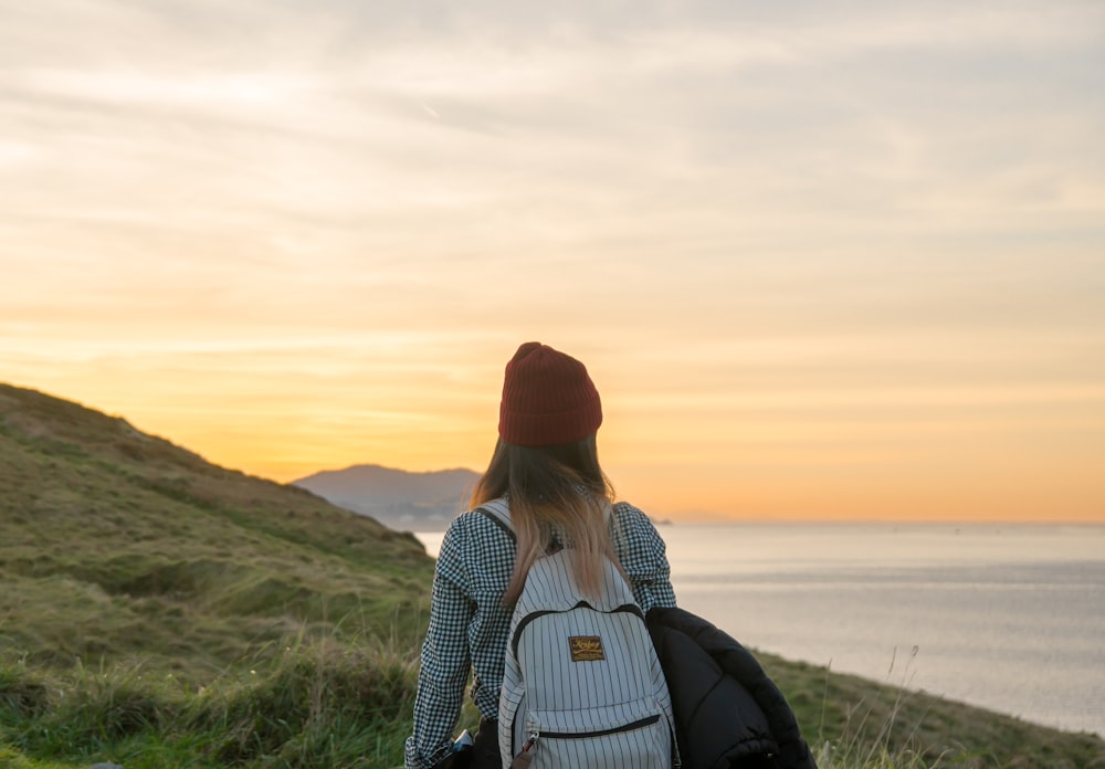 woman standing on cliff carrying backpack