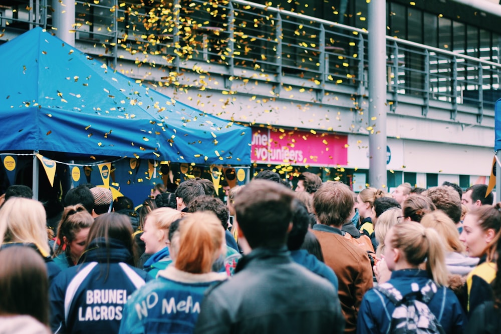 people celebrating outside building with flying confettis