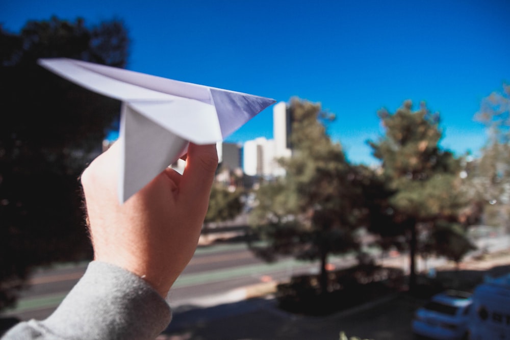 persona che tiene l'aeroplano di carta