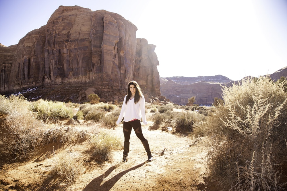 woman standing on green grass near brown mountain during daytime