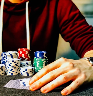 person holding playing cards beside poker chips