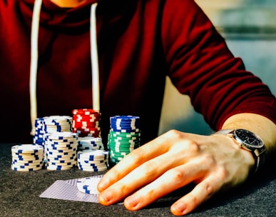 person holding playing cards beside poker chips