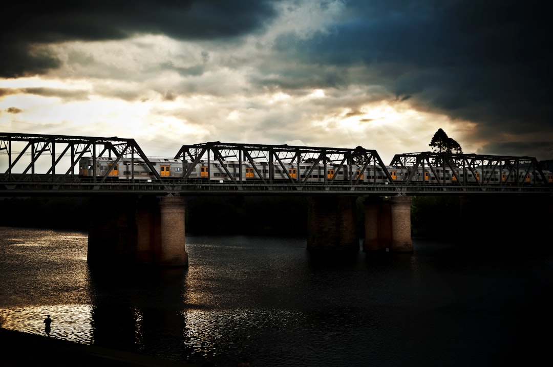 silhouette photography of bridge under nimbus clouds, A K-Set train crosses the Nepean river as an overcast sky illumina