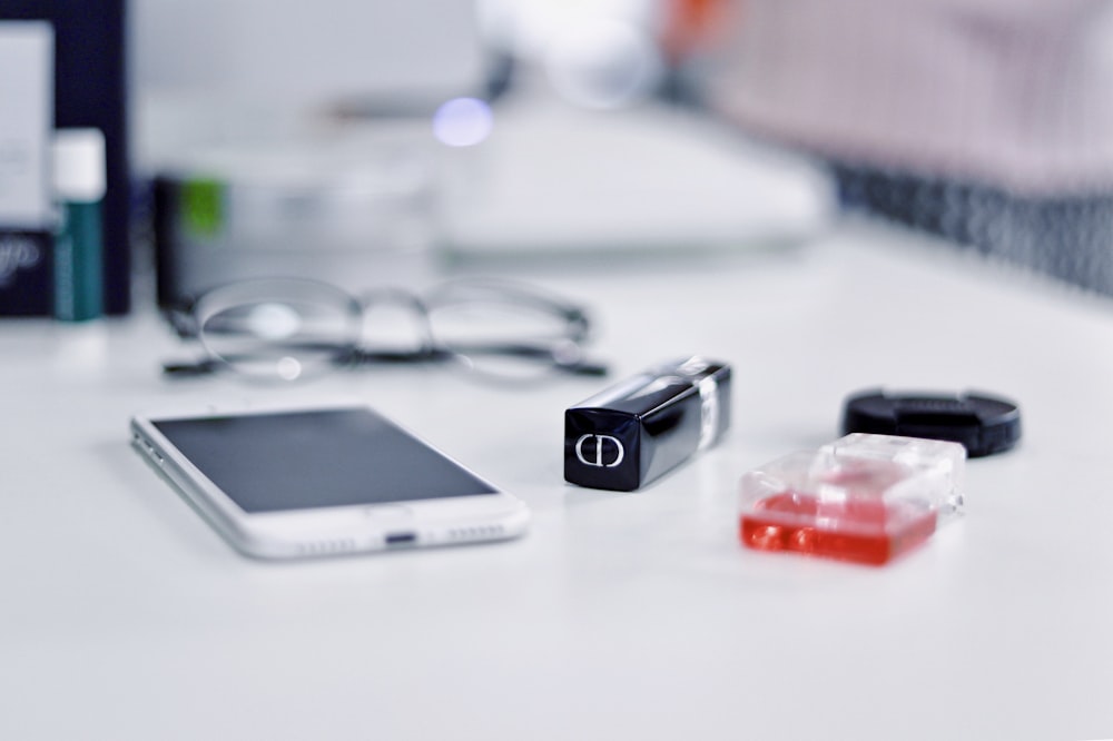 white smartphone and black framed eyeglasses behind