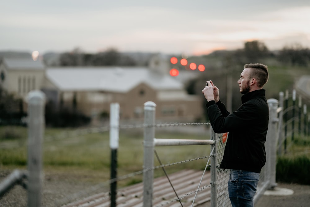 フェンスの近くで写真を撮る男性の浅い焦点の写真