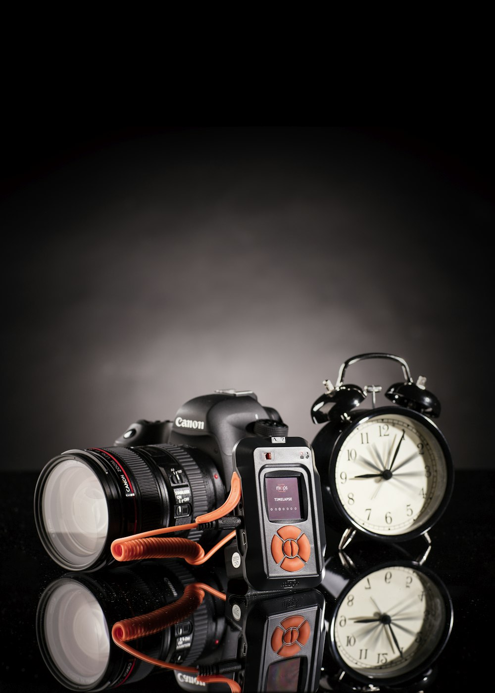 foto de la cámara Canon DSLR junto al reloj despertador negro de doble campana