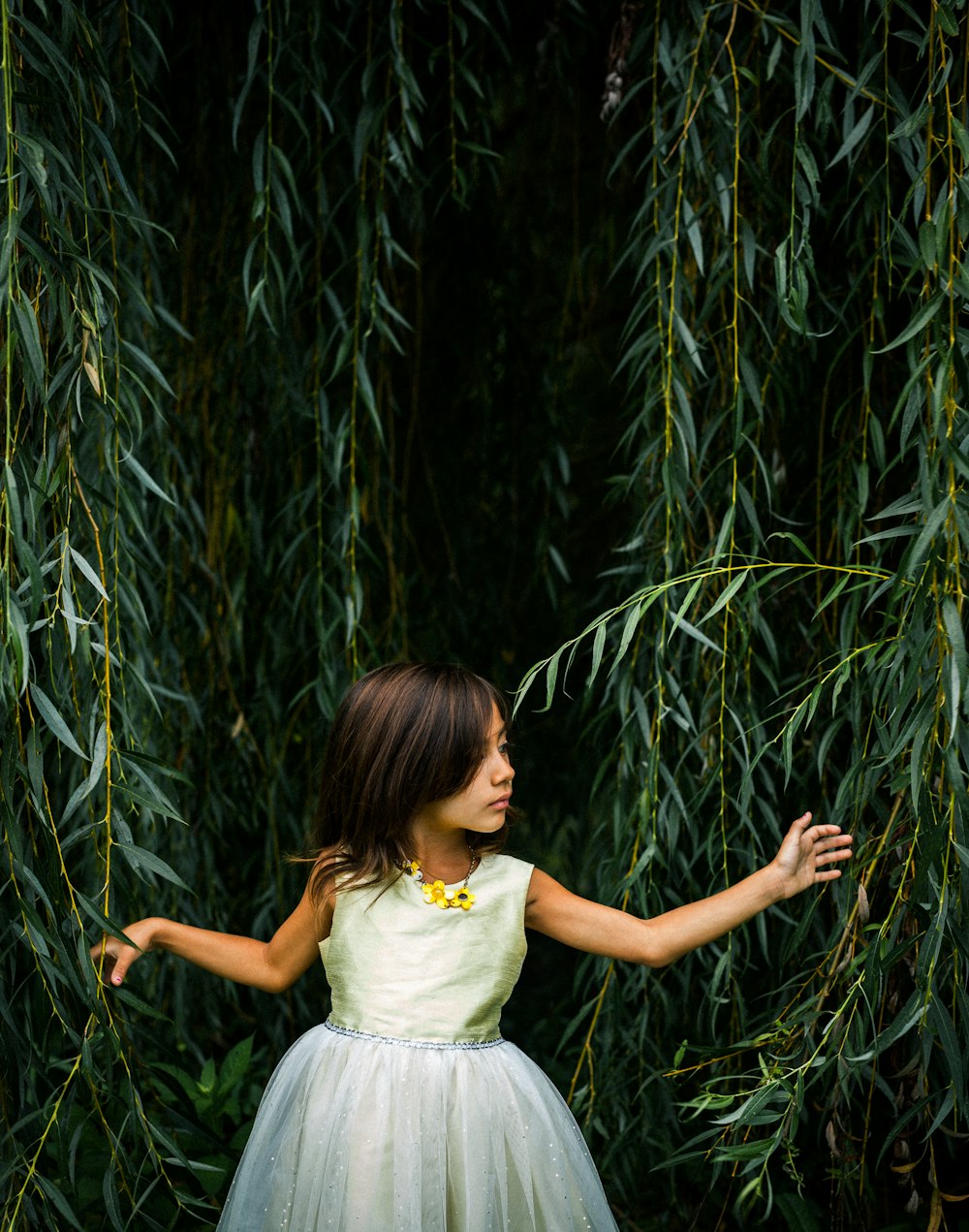 Muchacha con vestido de pie cerca de las plantas