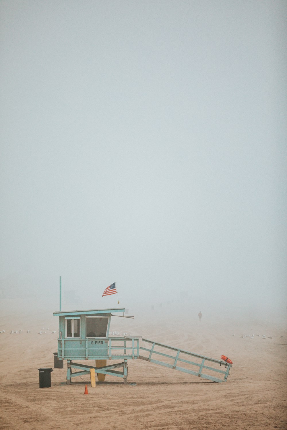 blue wooden lifeguard house near black plastic trash bin