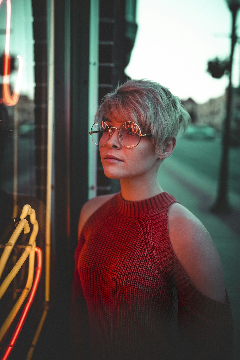 Frau mit Brille blickt auf Glasscheibe mit Neonreklame