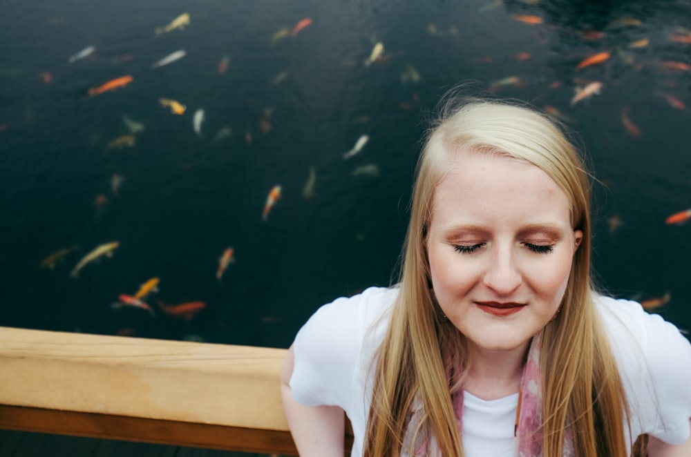 woman sitting while closing eye near water