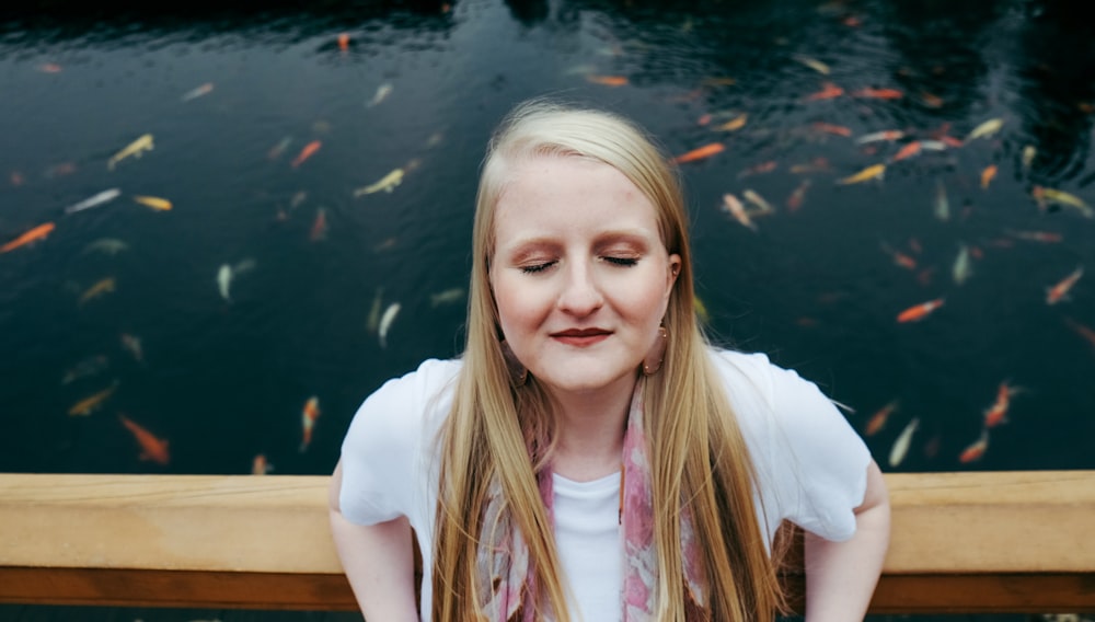 woman sitting on bench near koi pond