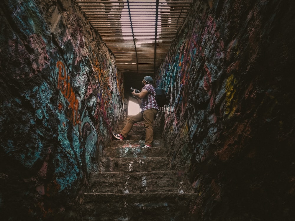 a man walking up a flight of stairs covered in graffiti