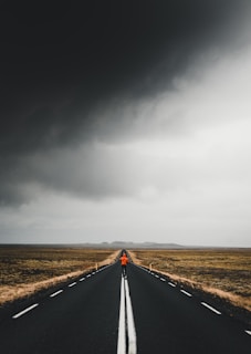 man under blacktop road under cloudy skies