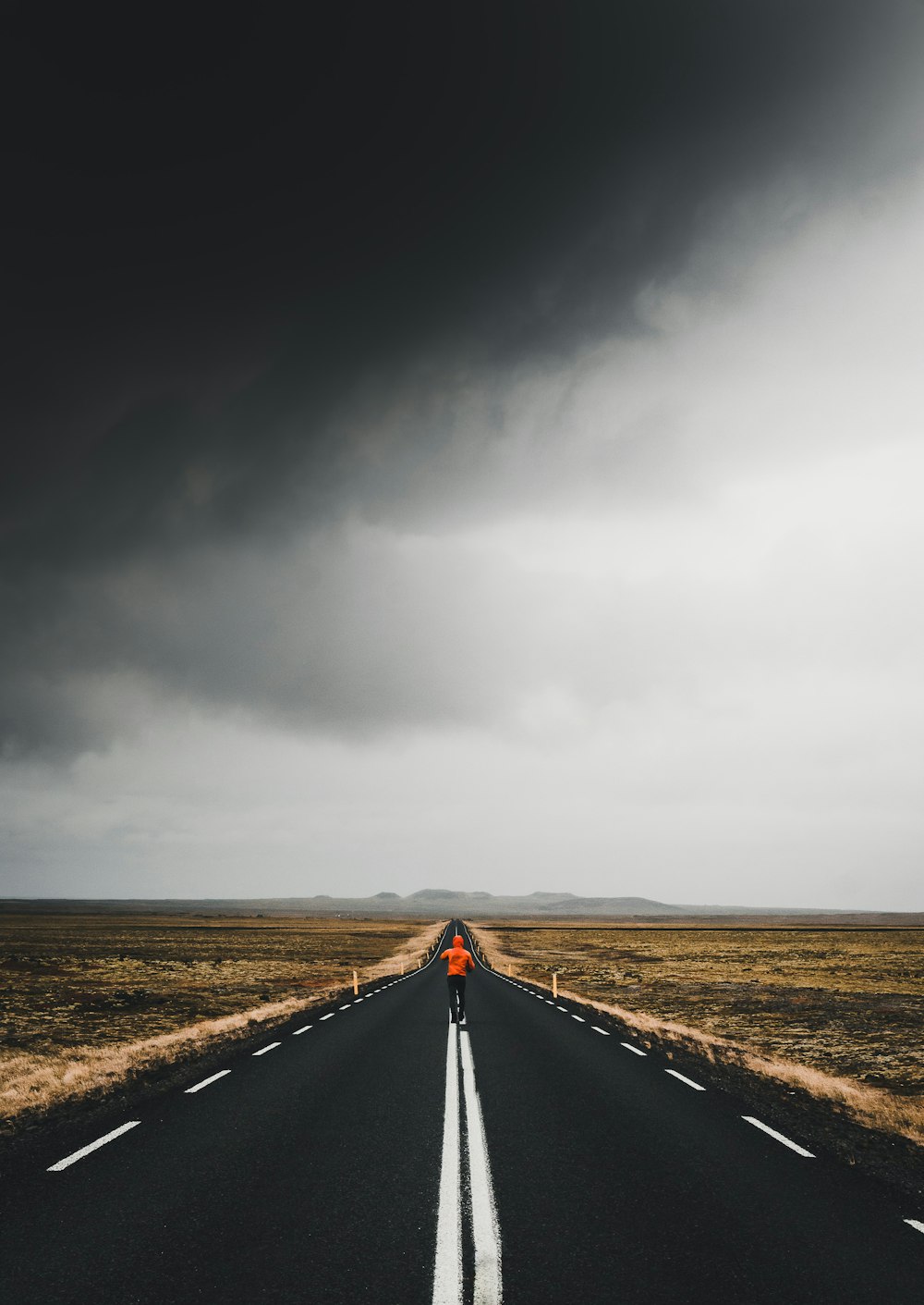 Hombre bajo el camino de asfalto bajo cielos nublados