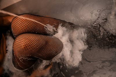 knee of woman wearing mesh stockings inside bathtub with water stocking stuffer zoom background