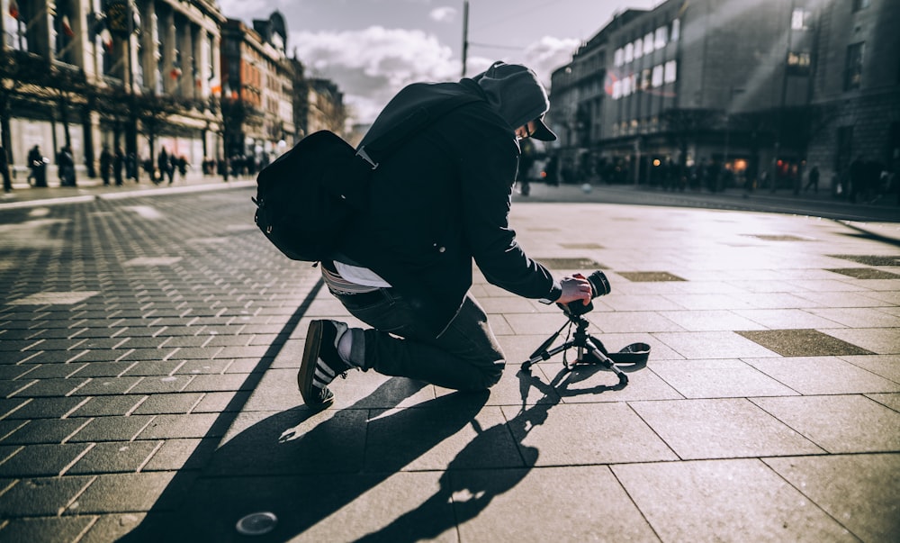 person kneeling on floor taking photo with sunlight