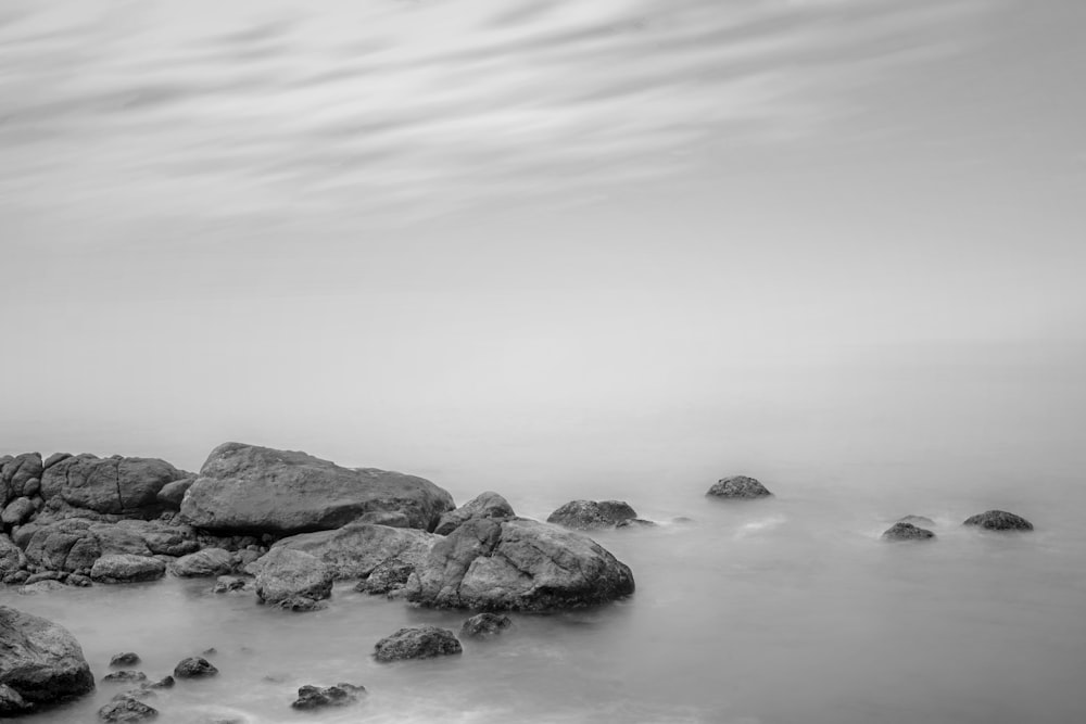 rocks beside body of water grayscale photography