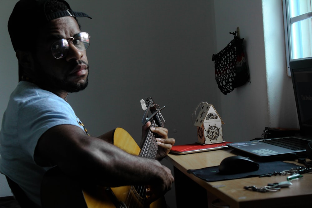 man playing guitar beside table