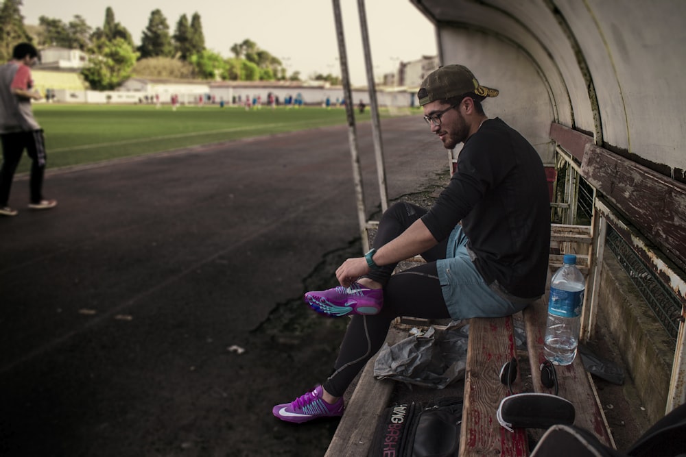 man tying his shoes while sitting on bench