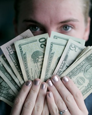 person holding fan of U.S. dollars banknote