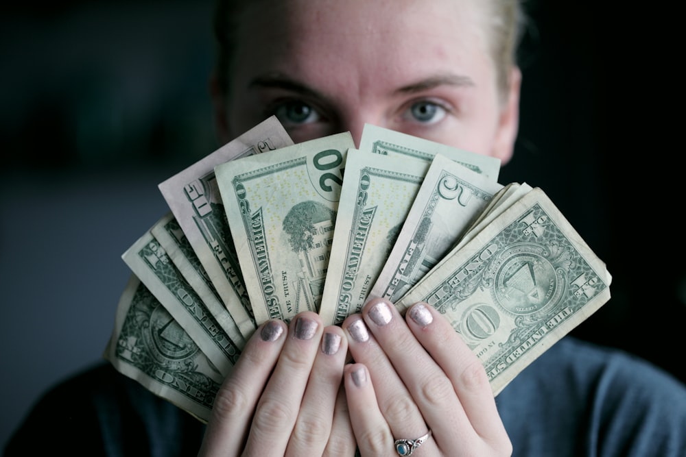 person holding fan of U.S. dollars banknote