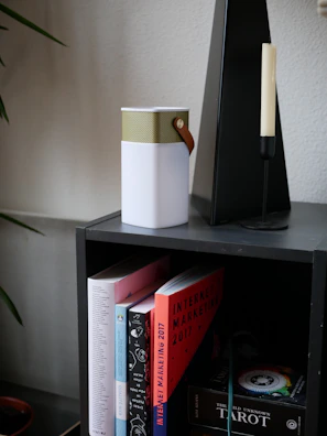 Minimalist black and gold wireless speaker placed on a modern shelf.