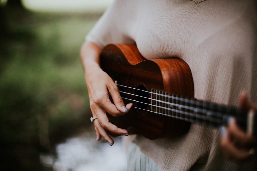 mulher que joga ukulele durante o dia