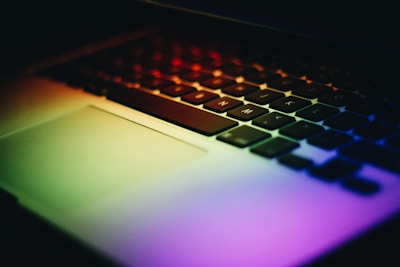 Close-up of hands typing on a laptop keyboard with subtle gradient lighting.