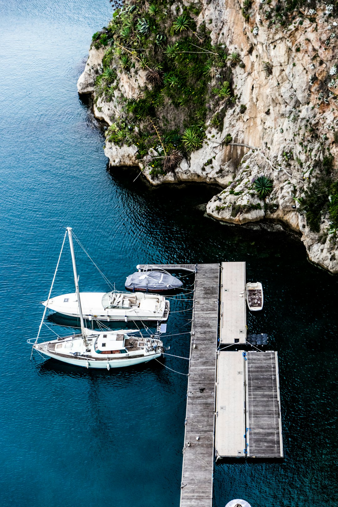 aerial photography of three yachts docking on wooden dock beside island