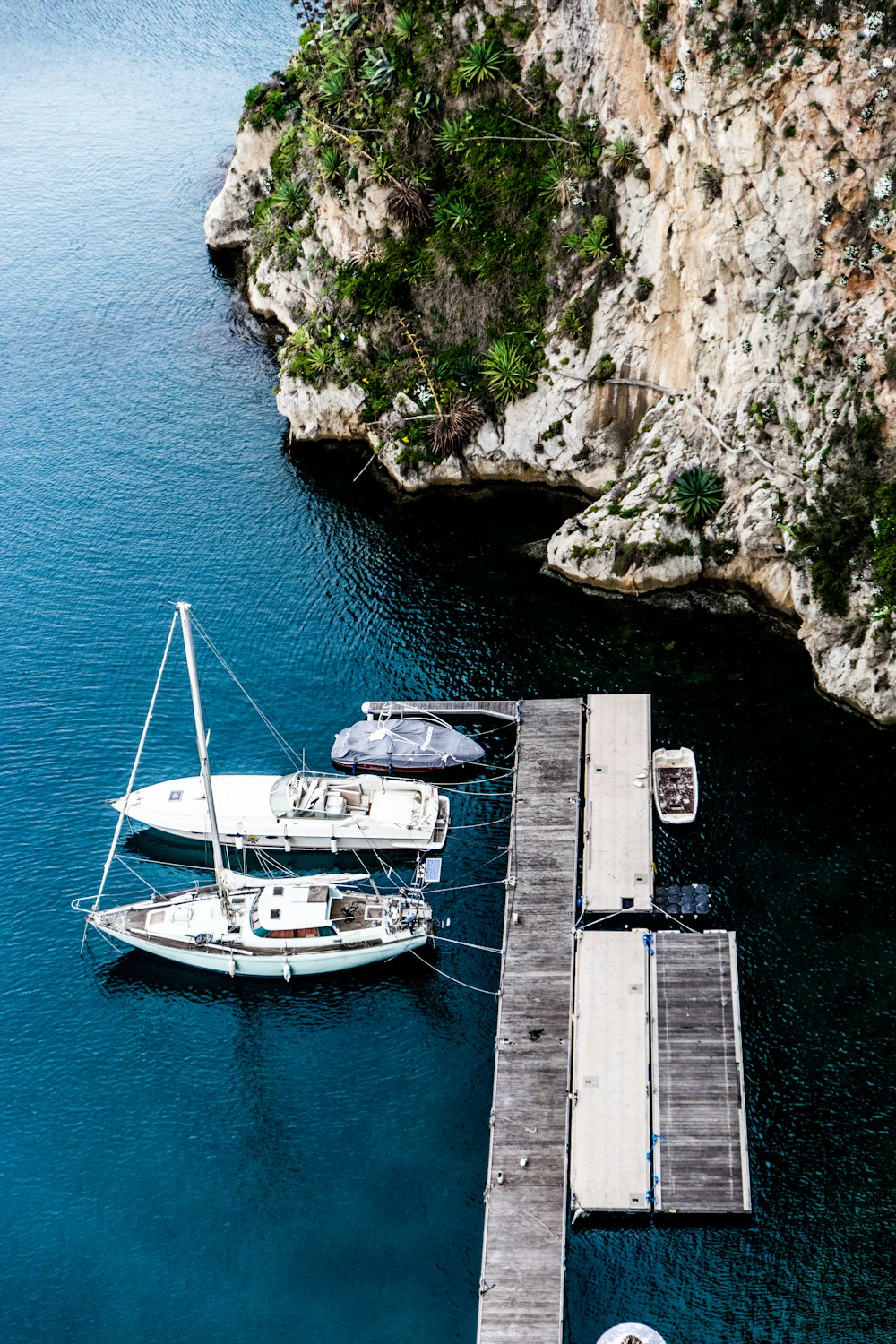 Photographie aérienne de trois yachts amarrés sur un quai en bois à côté de l’île