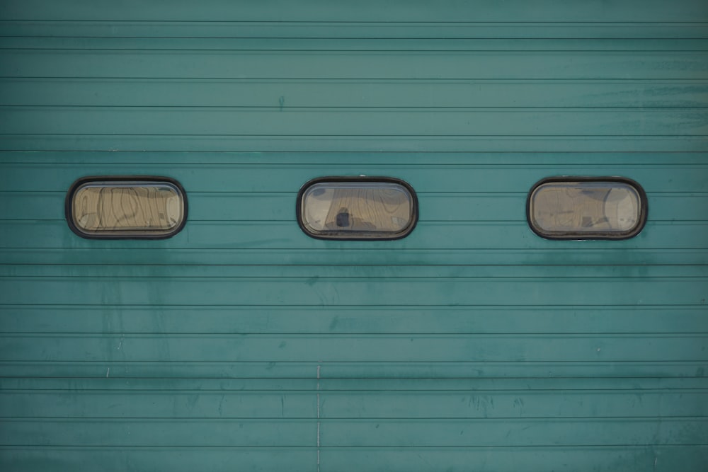 three windows on the side of a blue train