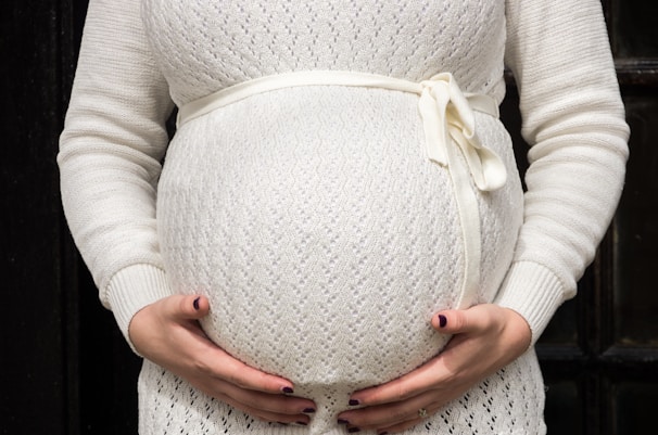 A cozy maternity sweater in soft pastel pink displayed on a mannequin.