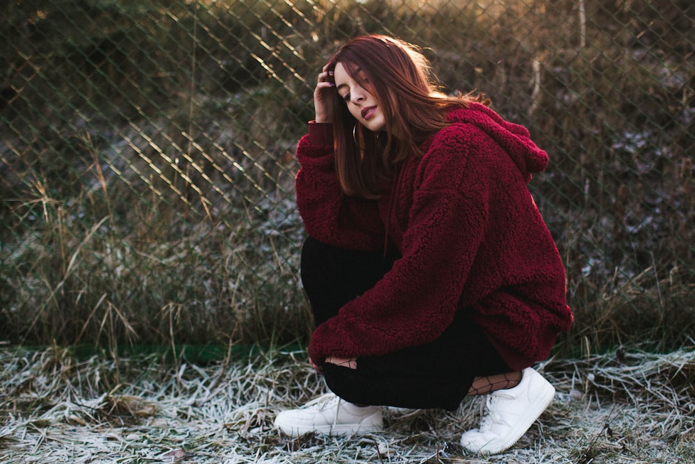 selective focus photography of woman half-sitting near fence