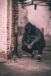 man sitting near brick wall
