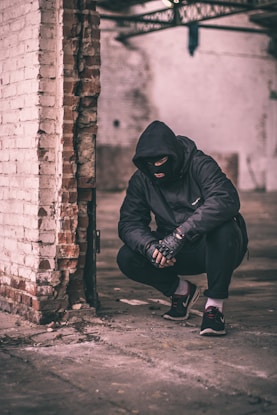 man sitting near brick wall