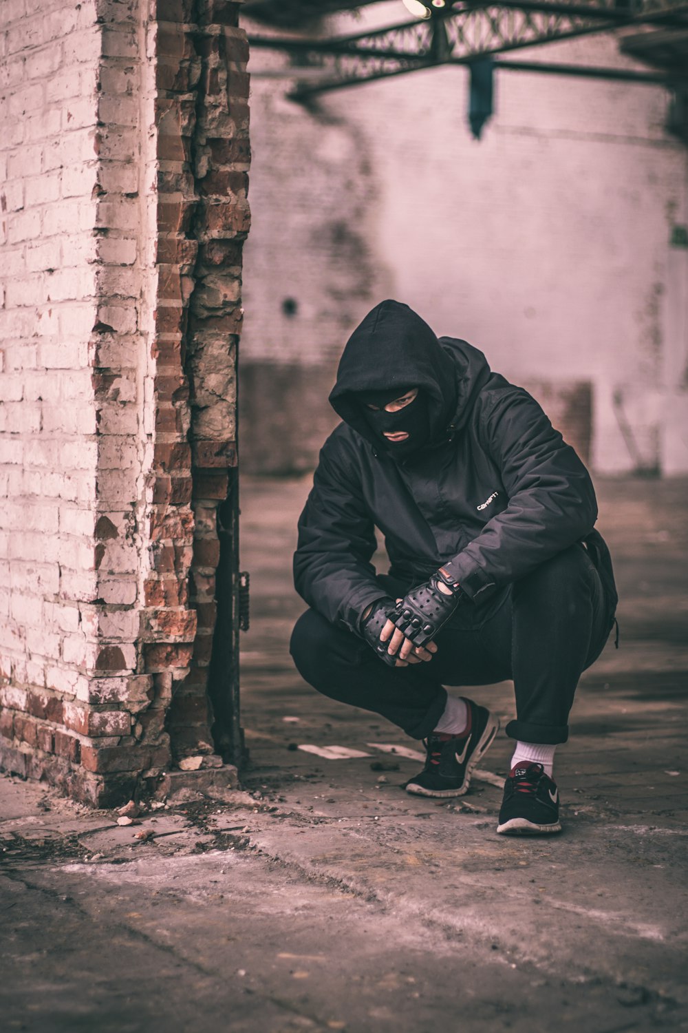 man sitting near brick wall