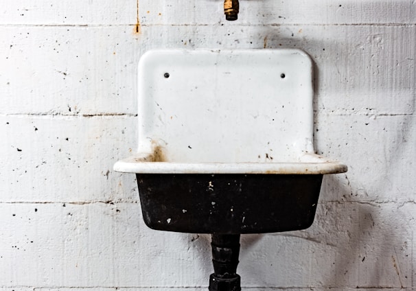 white and black sink beside wall