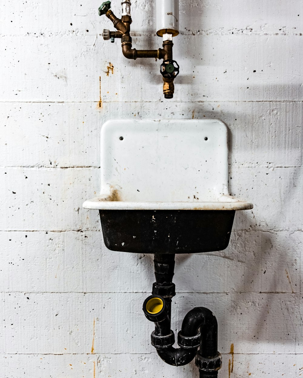 white and black sink beside wall